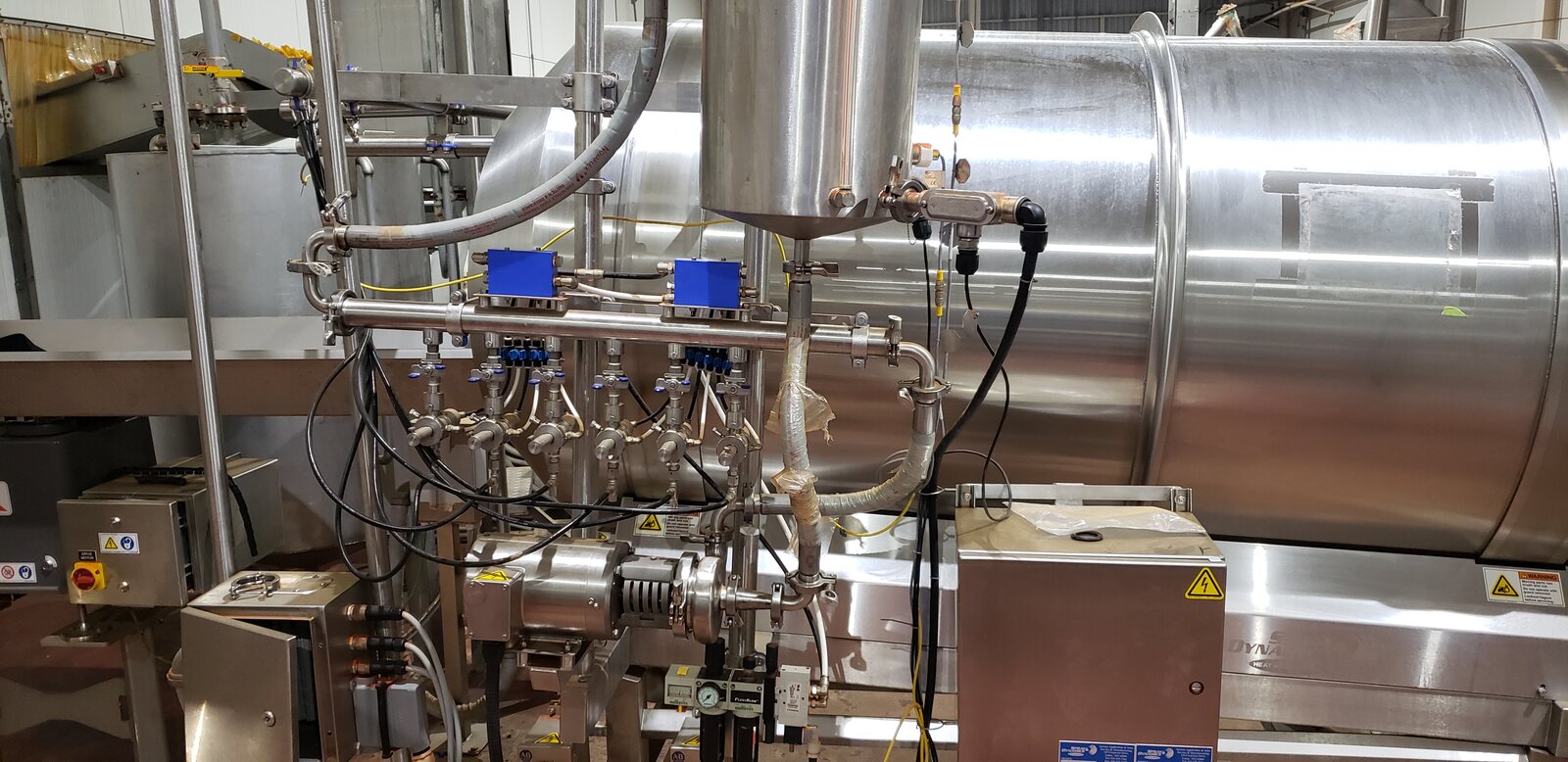 Stainless-steel process equipment with connected piping, valves, wiring, and motors.